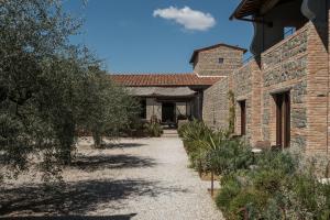 Außenansicht eines Steingebäudes mit einem Weg in der Unterkunft Borgo 69 Villas & Suites in Foiano della Chiana