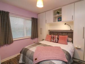 a bedroom with a bed with pink walls and a window at Long Jack's in Ballygarrett
