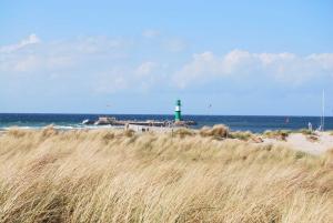 a lighthouse on the beach with a field of tall grass at Residenzen am Kirchenplatz in Warnemünde