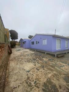 a blue house with a stone yard in front of it at Casa Ferrari pichilemu in Pichilemu
