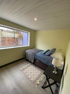 a bedroom with a bed and a window and a table at Casa Ferrari pichilemu in Pichilemu