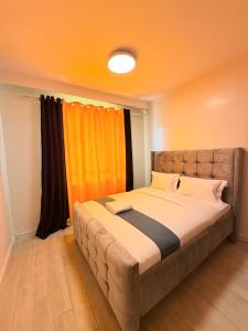 a bedroom with a large bed with an orange curtain at Ww homes 2bedroom Apartment in Nairobi +12 photos
