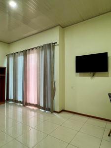 a living room with a flat screen tv on the wall at Aurora Hotel Siliwangi in Cirebon
