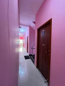 a hallway with pink walls and a wooden door at STAR Residency - G in Pondicherry