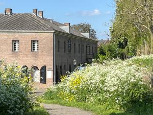 an old brick building with white flowers in front of it at de KruidenPoort in Woudrichem