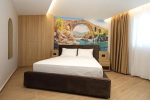 a bedroom with a bed with a painting on the wall at Vila Lira in Durrës +24 photos