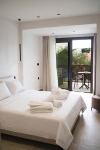 a bedroom with a white bed with towels on it at Malou and Charma Villas in Syvota