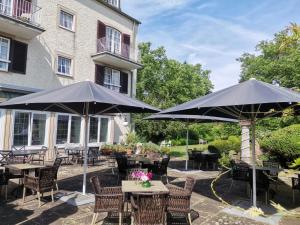 a patio with tables and umbrellas in front of a building at Hotel zum alten Brauhaus in Dudeldorf