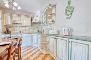 a kitchen with white cabinets and a wooden table at Quai secret in Niversac