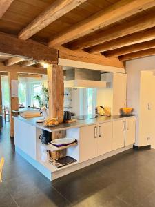 a large kitchen with white cabinets and wooden ceilings at La Ferme de Beauvoorde - 13 personnes in Steenvoorde