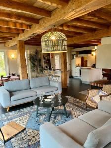 a living room with a couch and a table at La Ferme de Beauvoorde - 13 personnes in Steenvoorde