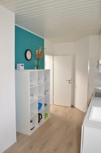a kitchen with white cabinets and a clock on a blue wall at Gästehaus Peter in Mettlach