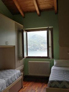 a green room with two beds and a window at Between mountains and lake in Carate Urio