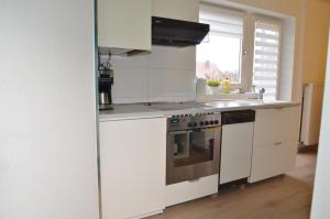 a white kitchen with a stove and a sink at Gästehaus Peter in Mettlach