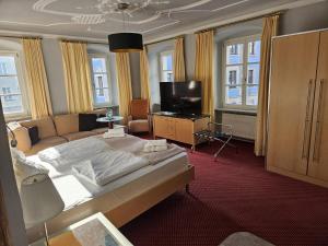 a bedroom with a bed and a couch and a television at Hotel Rose in Weißenburg in Bayern