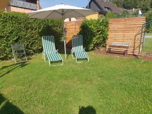 two chairs and an umbrella in a yard at Gästehaus Peter in Mettlach