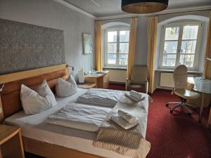 a bedroom with a bed and a desk and two windows at Hotel Rose in Weißenburg in Bayern