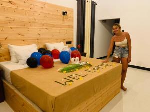 a woman standing next to a large bed with balloons on it at water lily heaven in Tangalle
