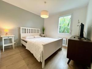 a bedroom with a white bed and a window at Maison Aquitaine "Tanchet" in Les Sables-d'Olonne