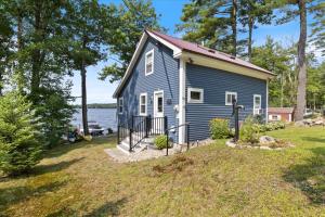 a blue house on the shore of a lake at Eagle's Landing Private Dock Dog Friendly in Acton