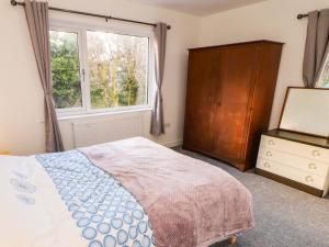 a bedroom with a bed and a dresser and a window at Westerlodge in Keswick