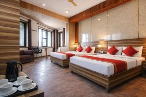 two beds in a hotel room with red pillows at Hotel Vijay Palace Dharamshala Himachal in Dharmsāla