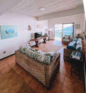 a living room with two couches and a television at Mar Infinito Guest House in Arraial do Cabo