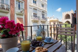 a table with a vase of flowers and orange juice at Blanquerias Apartments in Valencia