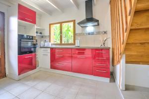 a red kitchen with white cabinets and a window at Le chalet sur Manoire in Saint-Laurent-sur-Manoire