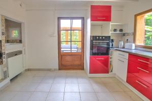 a kitchen with red cabinets and a red door at Le chalet sur Manoire in Saint-Laurent-sur-Manoire