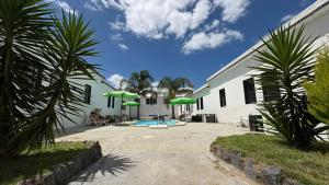a house with a swimming pool and green umbrellas at Piriápolis Hostel & suites in Piriápolis