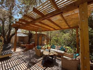 eine hölzerne Pergola mit Sofas und Stühlen auf einer Terrasse in der Unterkunft Hotel Jireh in San Pedro de Atacama