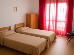 two beds in a room with red curtains at Dimora del Golfo in Soverato Marina