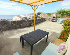 a black bench sitting on a patio with an umbrella at Casa do Portinho - Sea View House - in São Roque