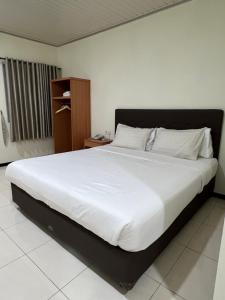 a bedroom with a large bed with white sheets at Aurora Hotel Siliwangi in Cirebon