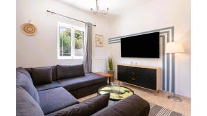 a living room with a couch and a flat screen tv at Ruvelis private pool villa in Fiolítis