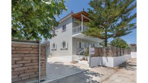 a white house with a wooden fence and a tree at Ruvelis private pool villa in Fiolítis