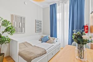 a white room with a bed and a table at Bright City Hideaway, Augarten and Danube - 5 min Metro - 10 min Center in Vienna