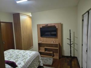a bedroom with a bed and a television on a wall at Portal Flores Suítes in Campos do Jordão