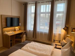 a hotel room with a bed and a desk with a television at Pension Zum Alten Fährhaus in Rostock