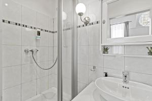 a white bathroom with a shower and a sink at Bright City Hideaway, Augarten and Danube - 5 min Metro - 10 min Center in Vienna