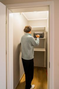 a woman is standing in front of a toaster oven at S12 Premium Apartments - by Hosty in Krakow +64 photos