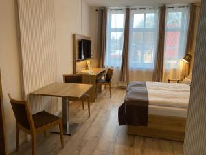 a hotel room with a bed and a desk and a table at Pension Zum Alten Fährhaus in Rostock