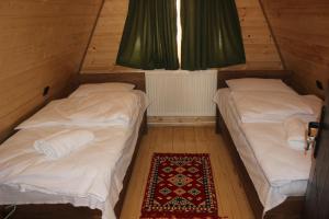 two beds in a small room with a rug at Zaga Cottage in Kazbegi