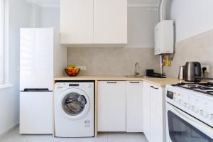 a kitchen with white cabinets and a washer and dryer at Quiet Kraków Nest by Siemaszki 41 in Krakow