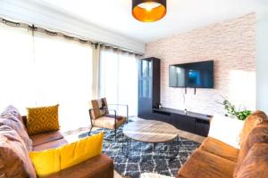 a living room with a couch and a tv at VILLA CITY GARDEN - Maison Spacieuse et Jardin - Proche Centre ville in Cholet