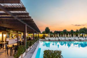 a hotel pool with chairs and a sunset at hu Venezia Camping in Town in Marghera