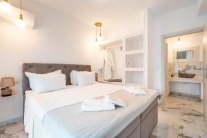 a bedroom with a large white bed with towels on it at Punta Mare Villas in Karpathos