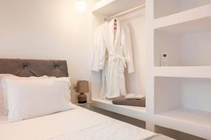 a bedroom with a bed and a robe on a shelf at Punta Mare Villas in Karpathos