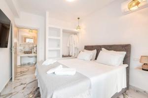 a white bedroom with a large bed with white sheets at Punta Mare Villas in Karpathos